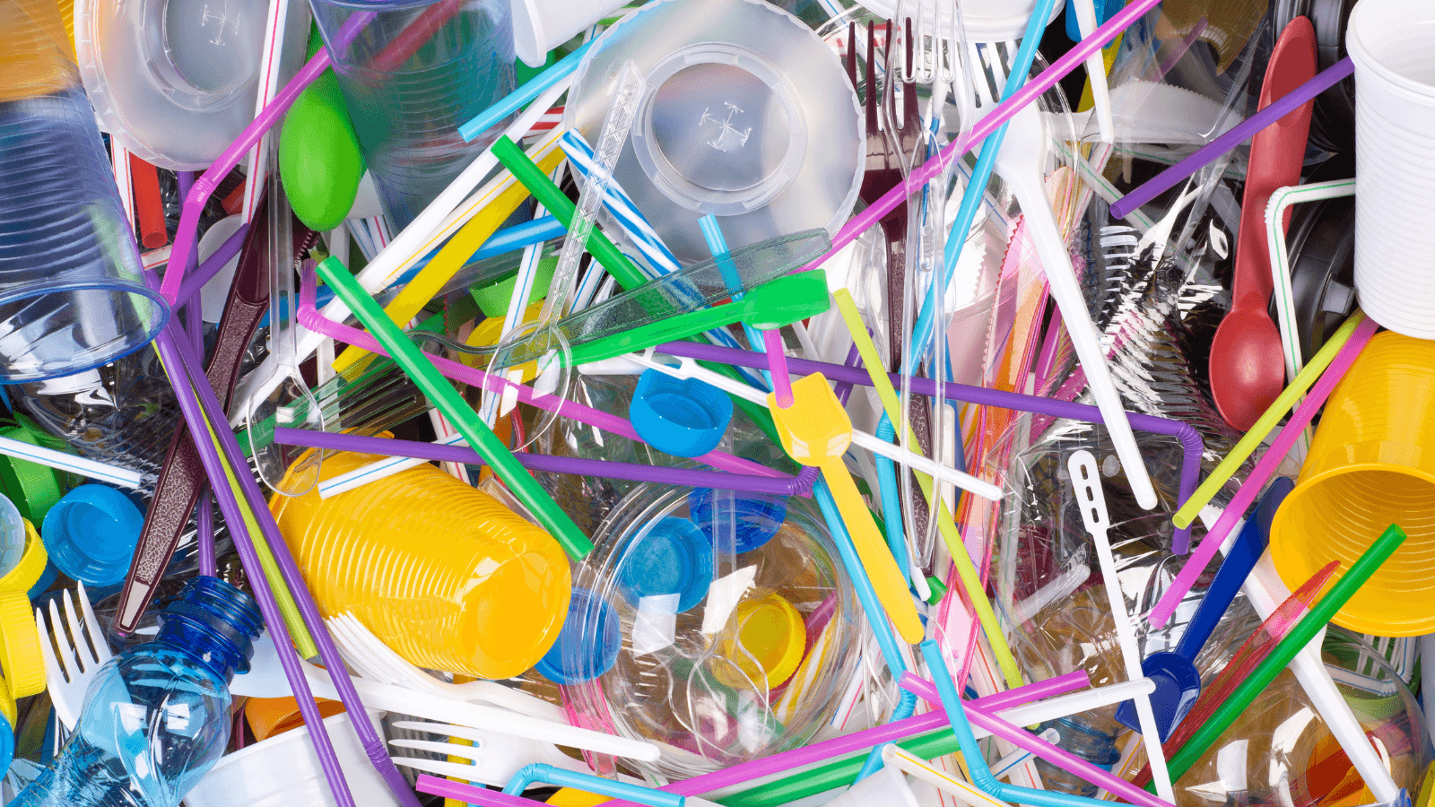 Disposable single use plastic objects such as bottles, cups, forks, spoons and drinking straws that cause pollution of the environment, especially oceans. Top view.